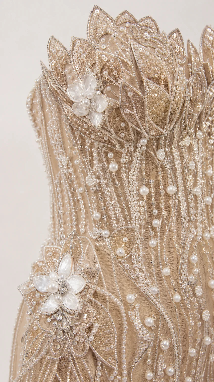 Close-up detail of 3D beaded floral appliques, pearl accents, and embroidery on sheer mesh